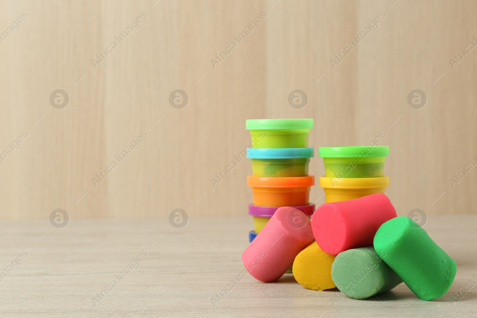 Photo of Different color play dough on white wooden table. Space for text