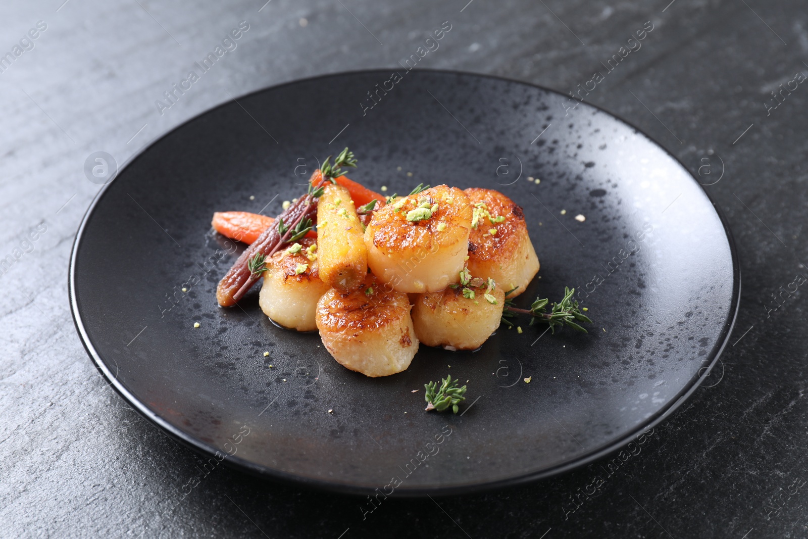 Photo of Delicious fried scallops on dark gray textured table, closeup