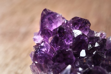 Photo of Beautiful purple amethyst gemstone on blurred brown background, closeup