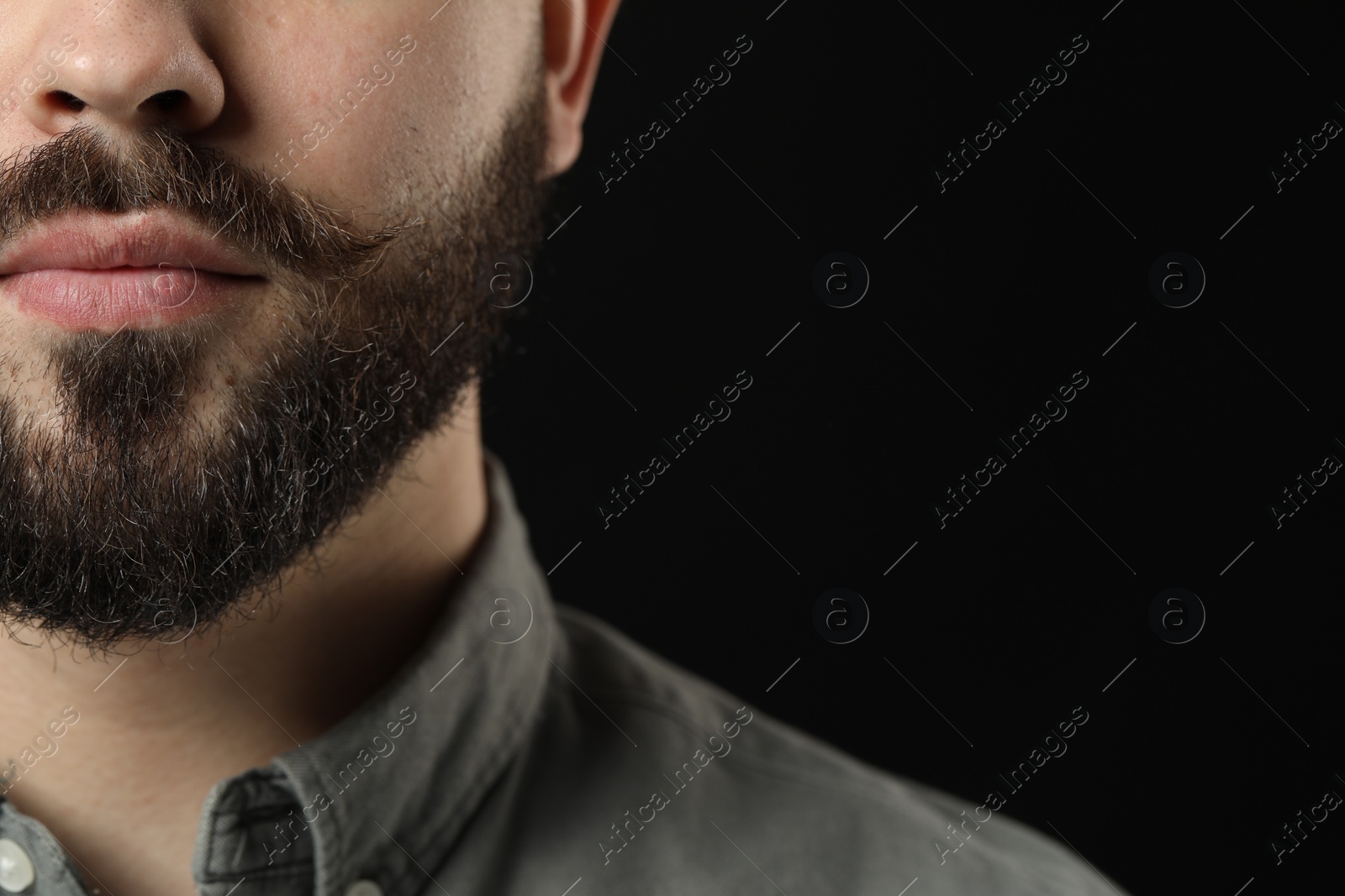 Photo of Handsome young man with mustache on black background, closeup