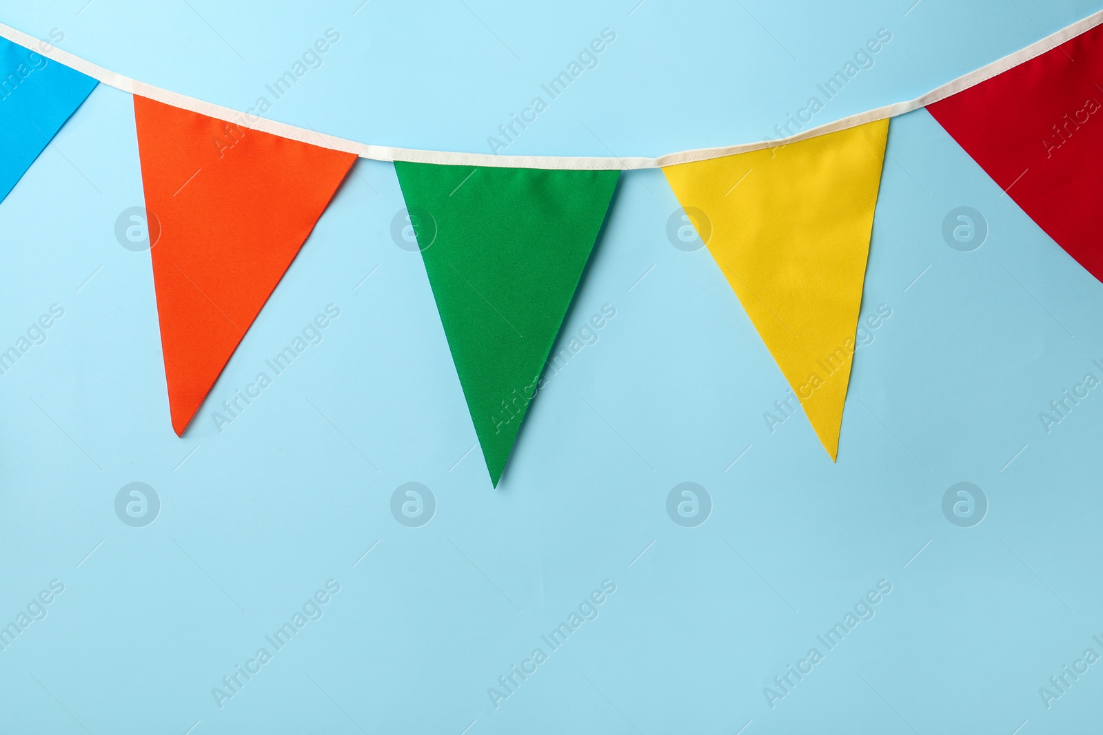 Photo of Bunting with colorful triangular flags on light blue background