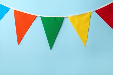 Photo of Bunting with colorful triangular flags on light blue background