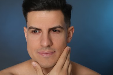 Photo of Handsome man after shaving on blue background, closeup