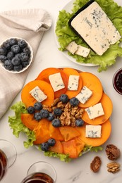 Delicious persimmon with blue cheese on white marble table, flat lay