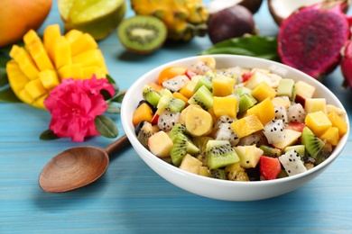 Delicious exotic fruit salad on light blue wooden table