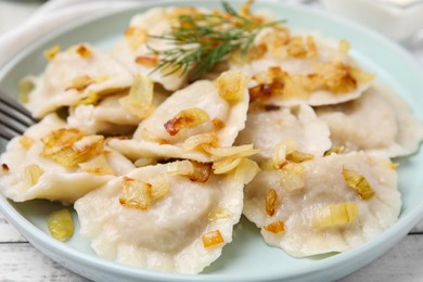 Photo of Cooked dumplings (varenyky) with tasty filling and fried onions on plate, closeup