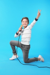 Cute boy with microphone on color background