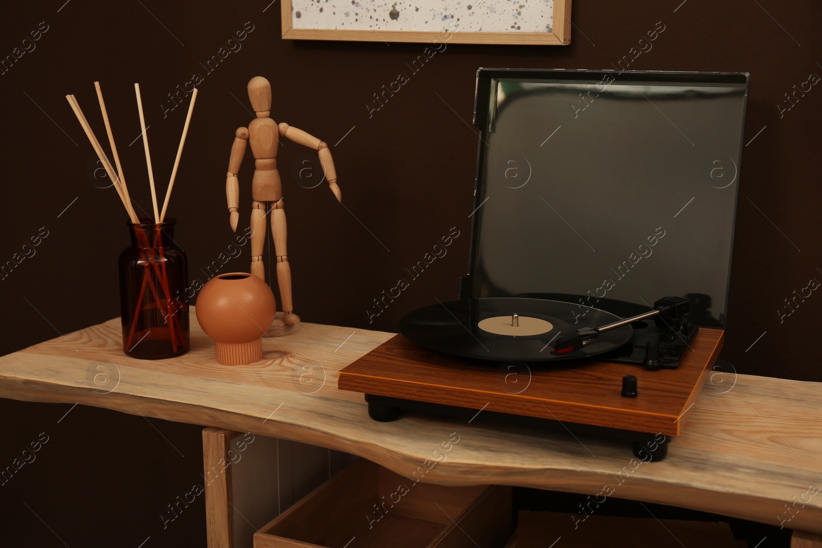 Photo of Modern turntable with vinyl disc on wooden table indoors. Interior design