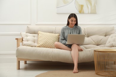 Young woman using laptop on sofa at home. Internet shopping