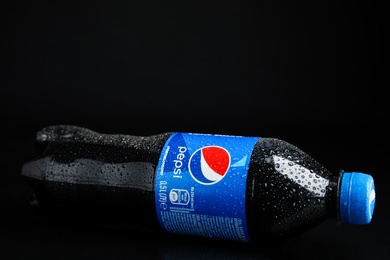 MYKOLAIV, UKRAINE - FEBRUARY 08, 2021: Plastic bottle of Pepsi with water drops on black background