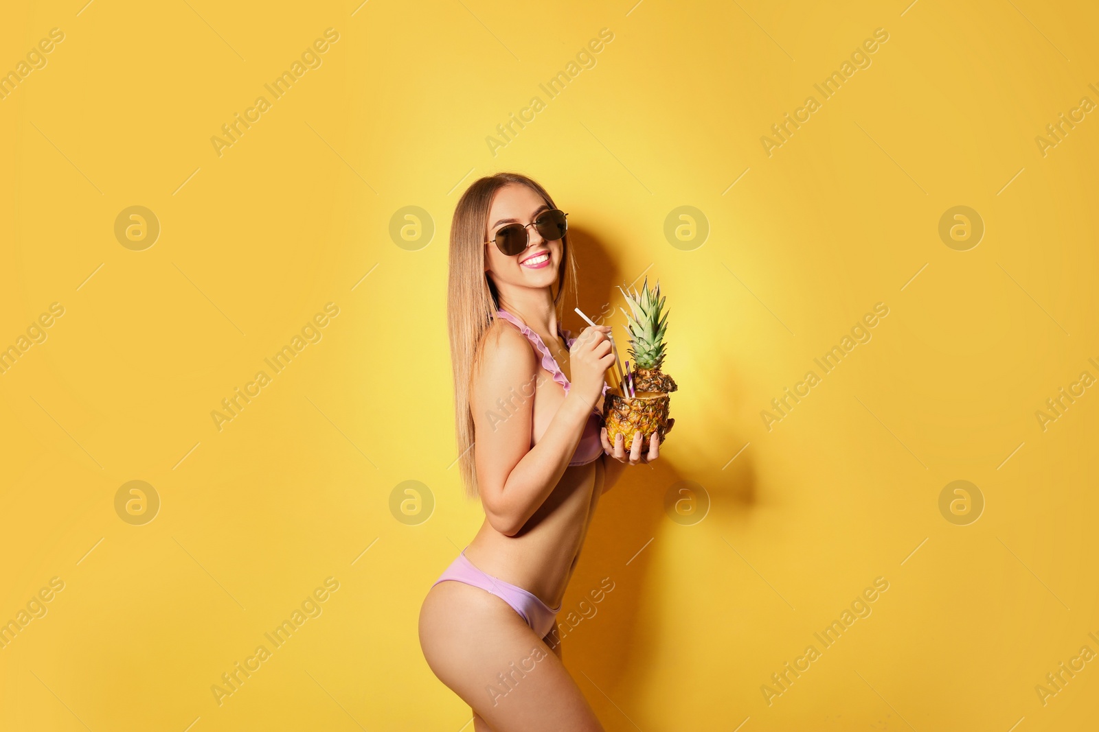 Photo of Pretty sexy woman in stylish bikini with cocktail on color background