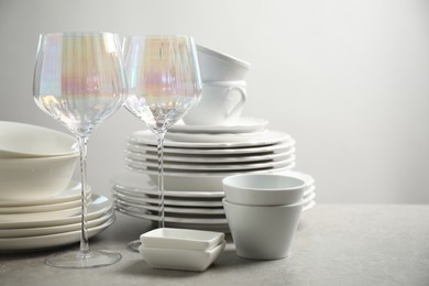 Set of clean dishes and glasses on light grey table