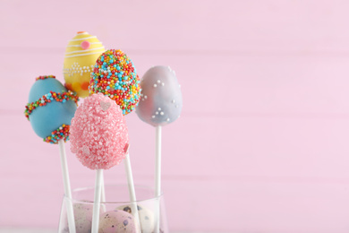 Closeup view of delicious sweet cake pops on light pink background, space for text. Easter holiday