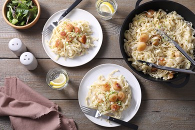 Delicious scallop pasta with onion served on wooden table, flat lay