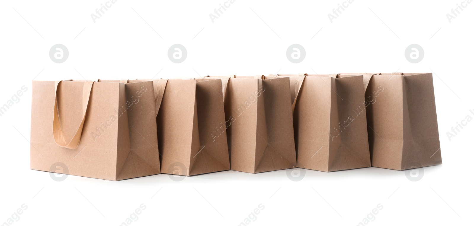 Photo of Paper shopping bags with comfortable handles on white background. Mockup for design