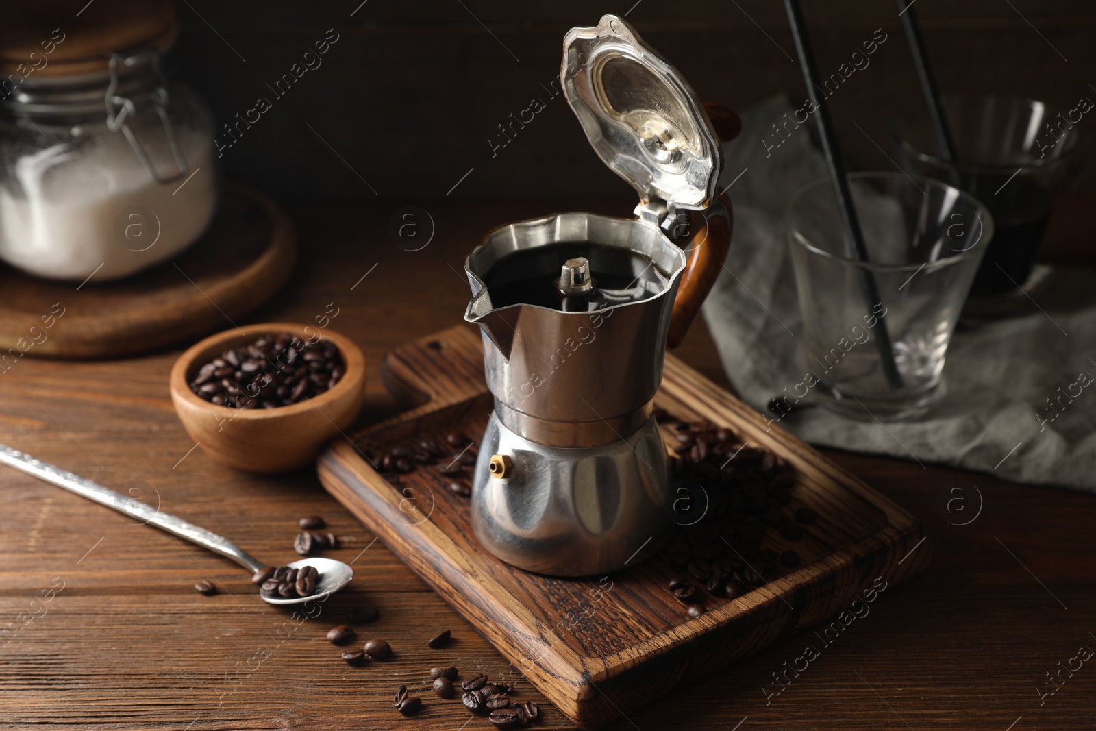 Photo of Brewed coffee in moka pot and beans on wooden table