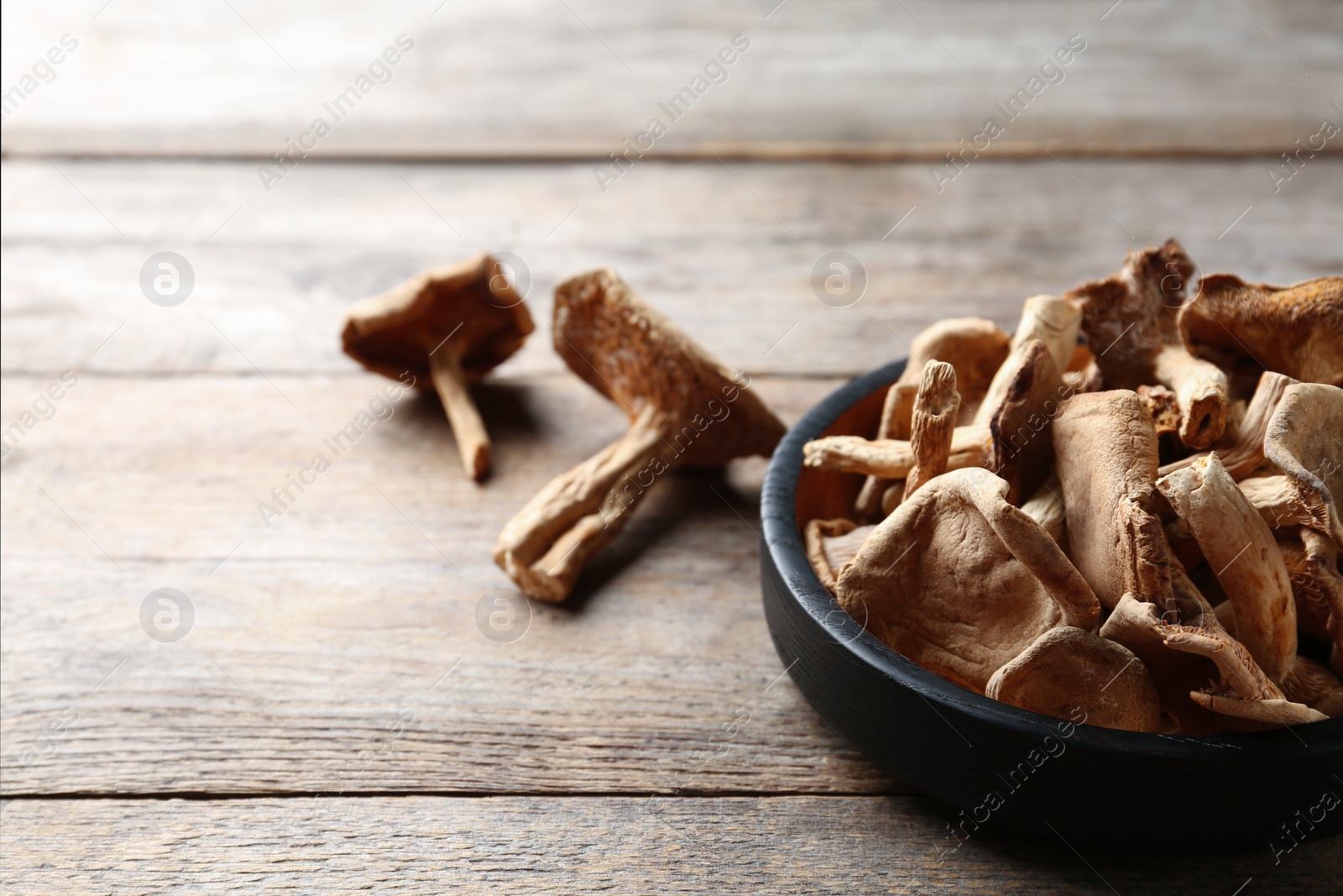 Photo of Composition of dried mushrooms and plate on wooden background. Space for text