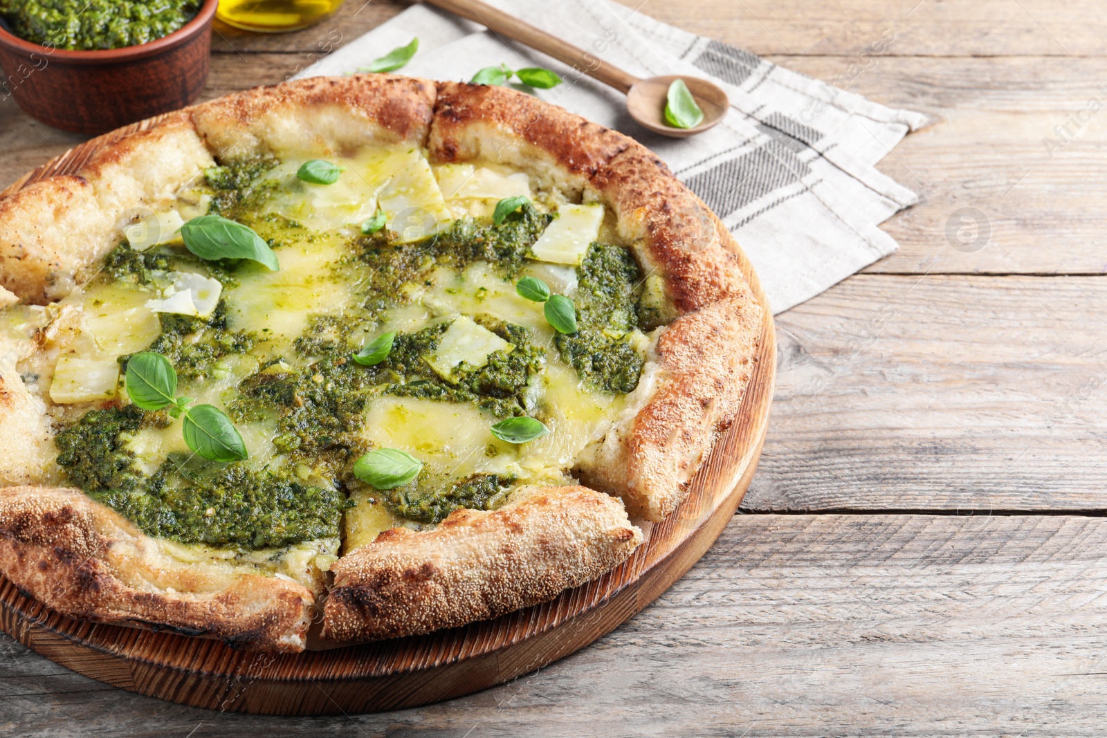 Photo of Delicious pizza with pesto, cheese and basil on wooden table. Space for text