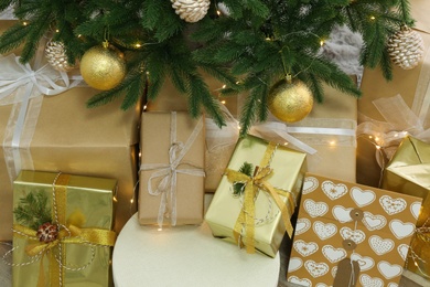 Photo of Pile of gift boxes near Christmas tree with fairy lights