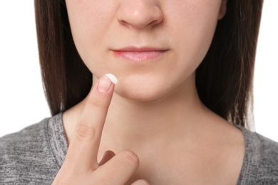 Photo of Young woman applying cold sore cream on lips, closeup