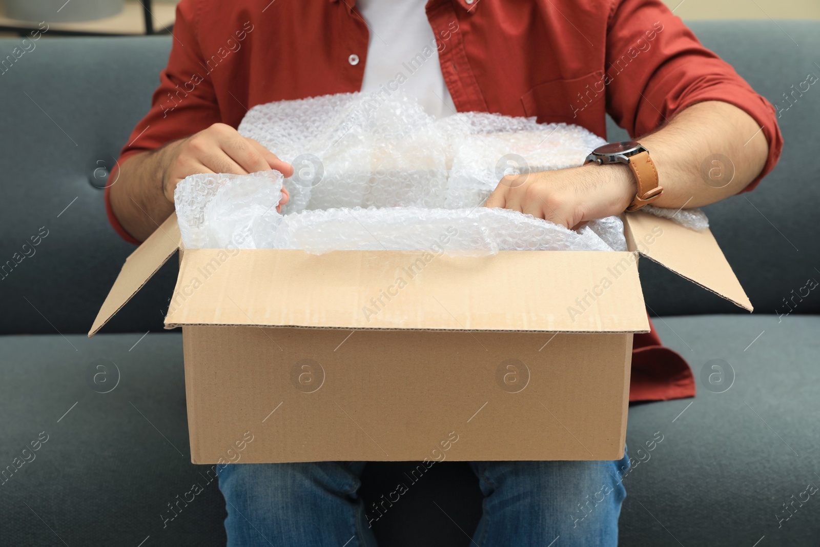 Photo of Man unpacking parcel at home, closeup. Online shopping