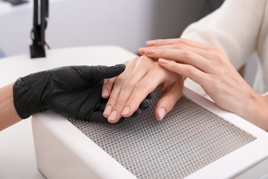 Professional manicurist working with client at white table, closeup