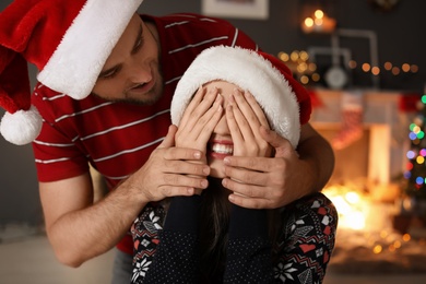 Photo of Happy young couple in Santa hats celebrating Christmas at home