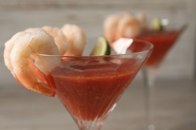 Photo of Tasty shrimp cocktail with sauce in glasses on table, closeup