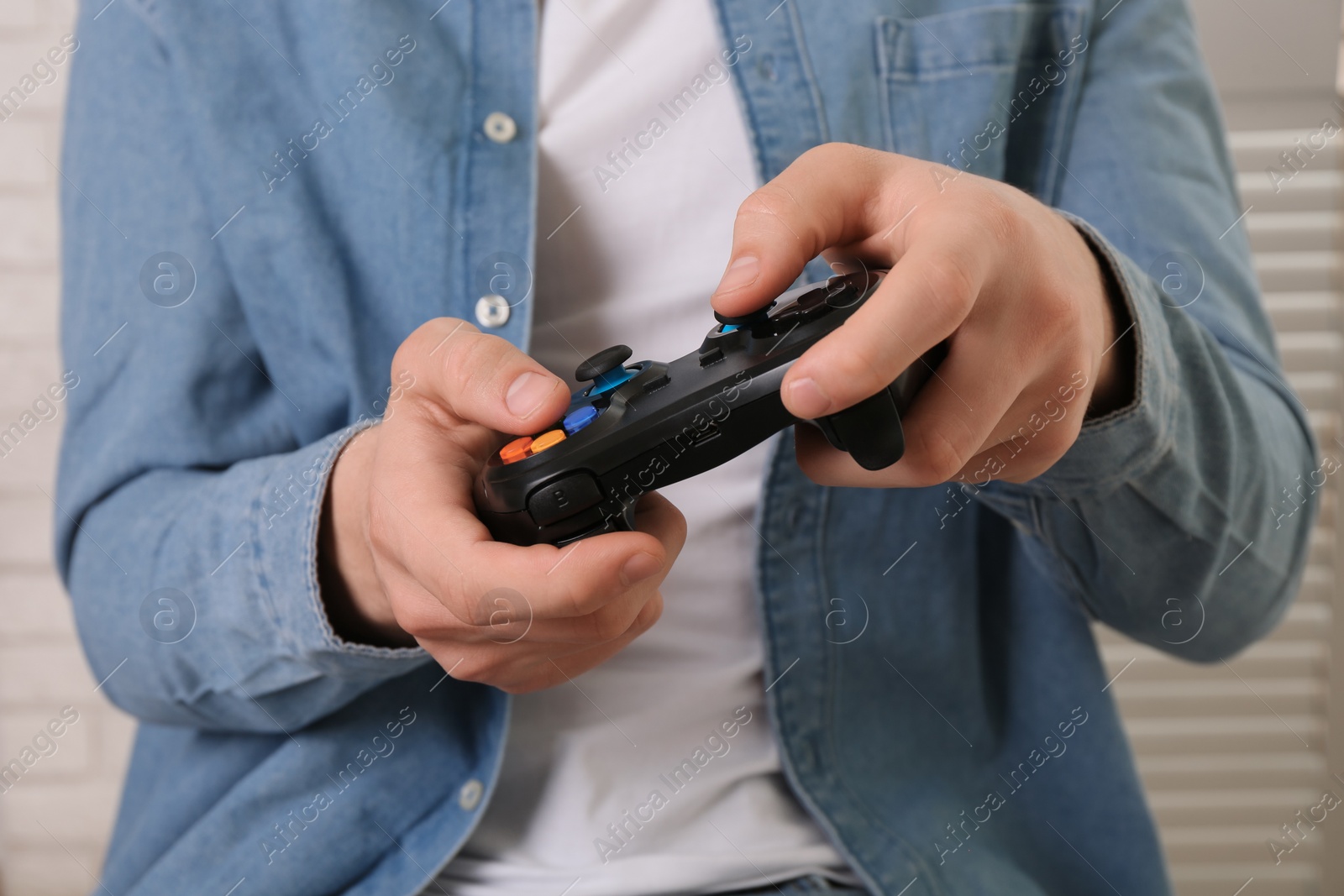 Photo of Man using wireless game controller indoors, closeup