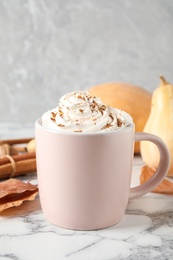 Cup with tasty pumpkin spice latte on white marble table