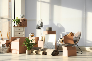 Photo of Cardboard boxes and household stuff in living room. Moving day