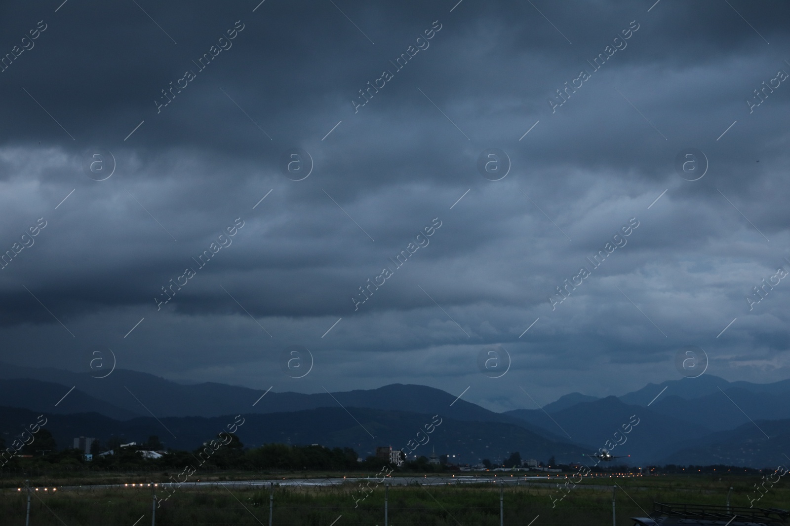 Photo of Modern white airplane above takeoff runway in evening