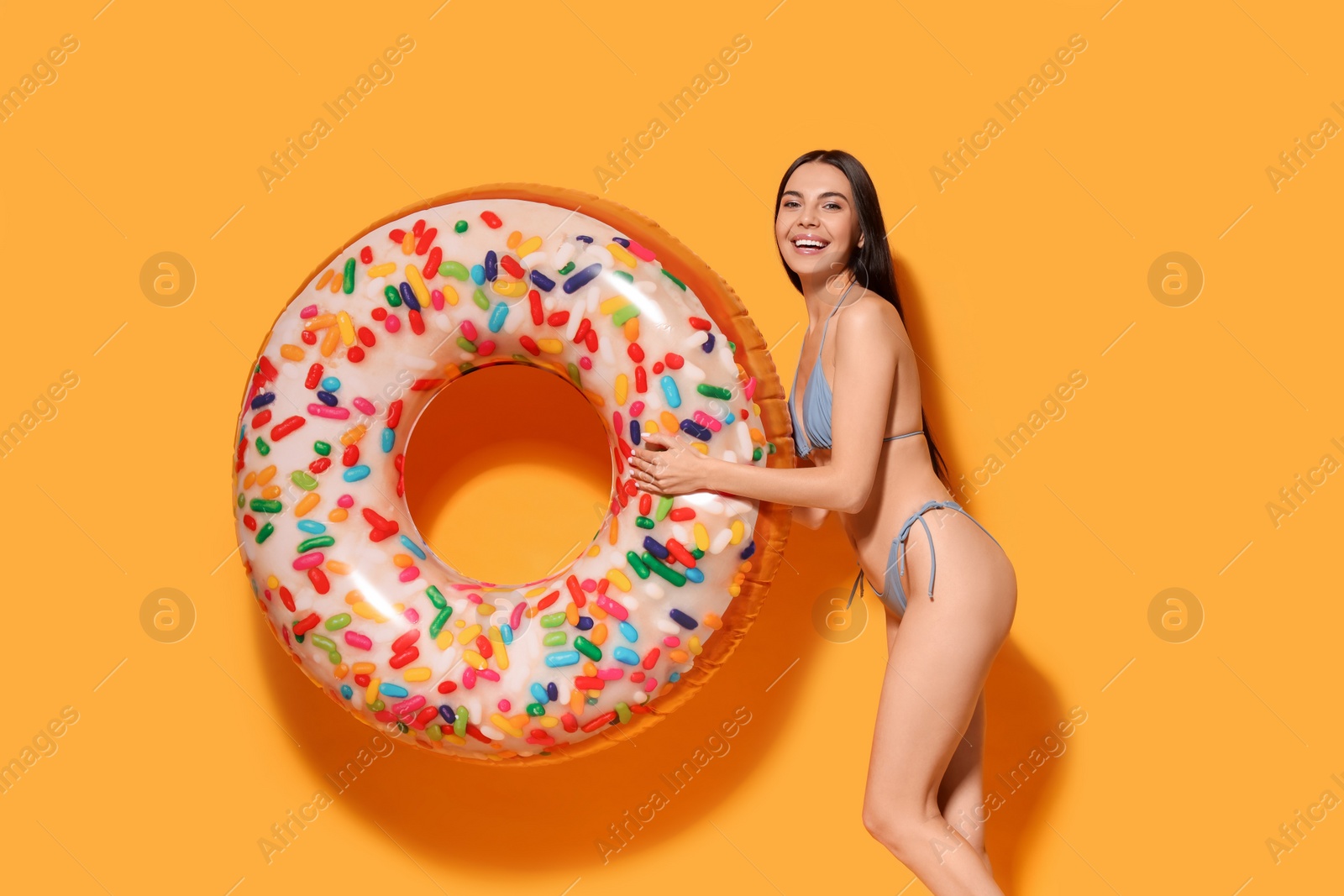 Photo of Young woman with inflatable ring against orange background