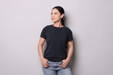 Photo of Woman wearing black t-shirt on light grey background