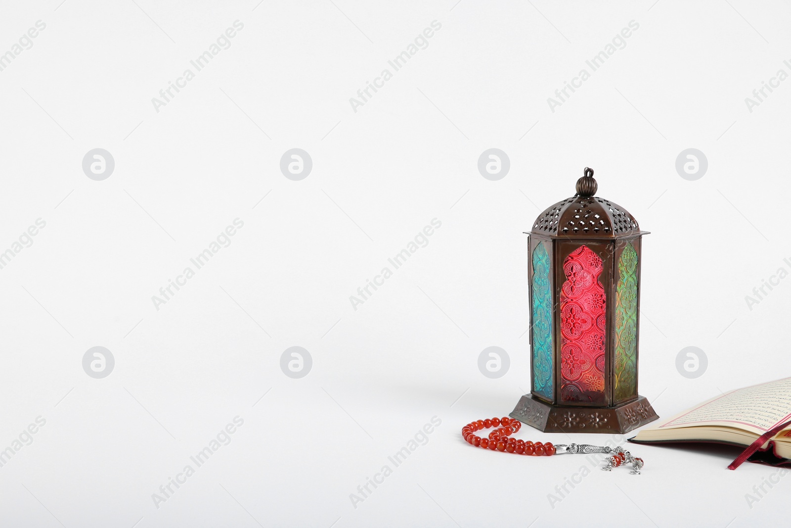 Photo of Muslim lamp, Koran and prayer beads on white background. Space for text