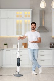 Photo of Happy man with steam mop in kitchen at home