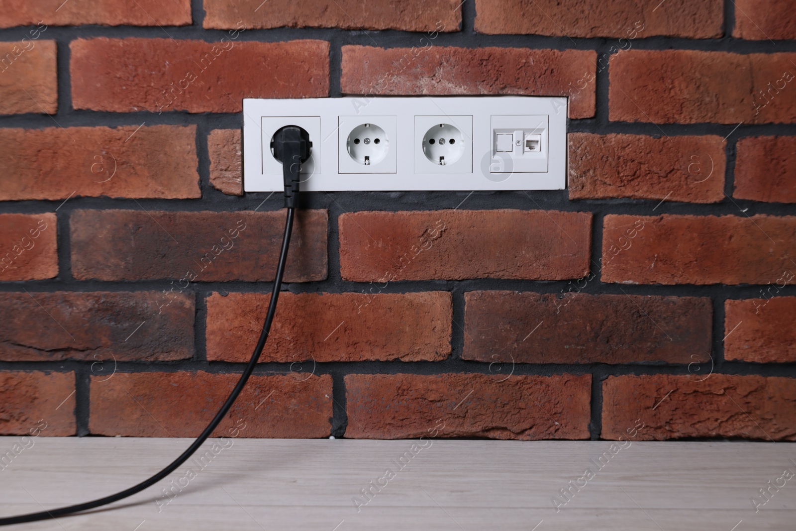 Photo of Power sockets and electric plug on brick wall