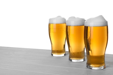 Photo of Glasses of tasty beer on wooden table against white background. Space for text