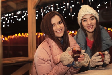 Friends with glass cups of mulled wine at winter fair