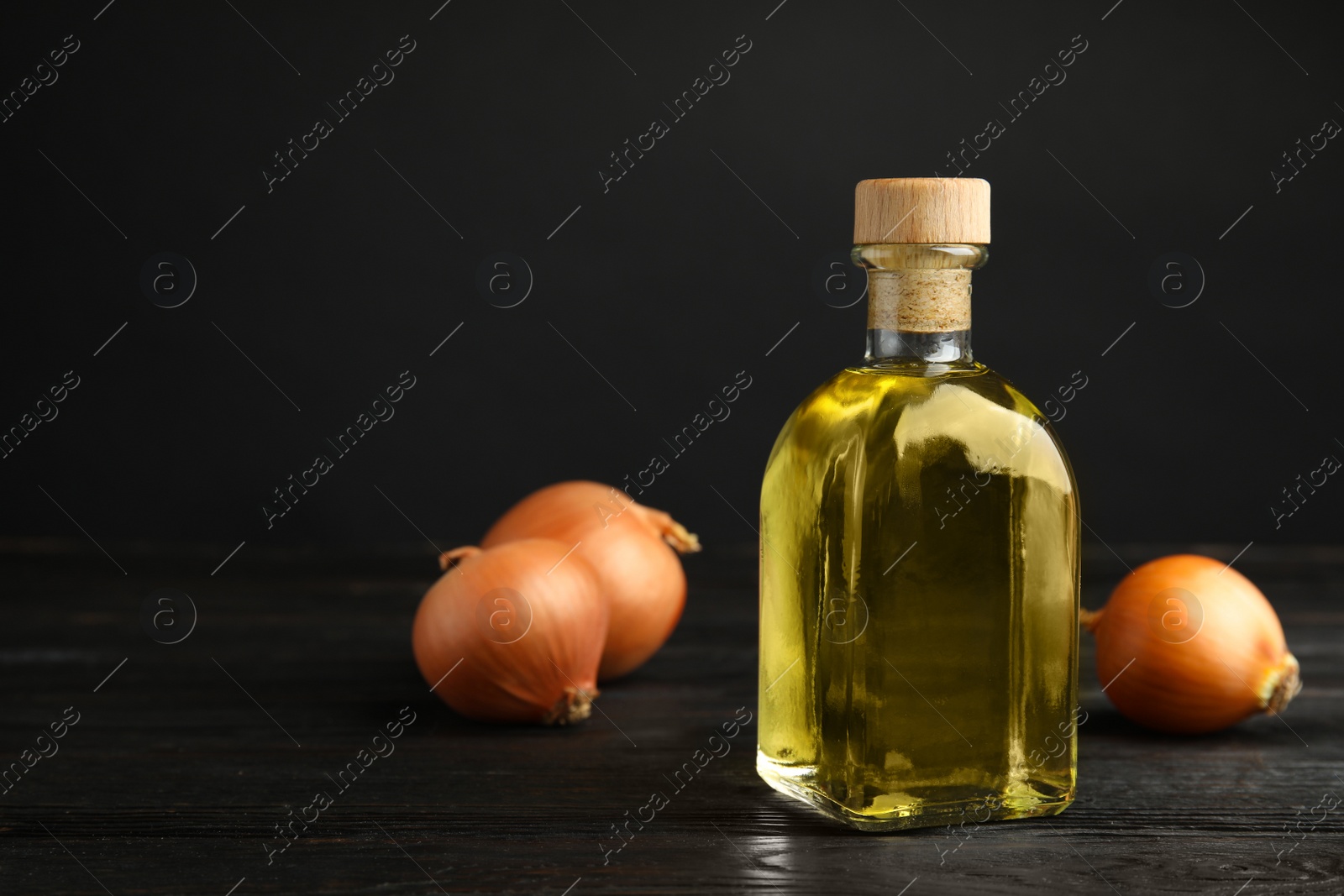 Photo of Glass bottle of onion syrup and fresh vegetable on dark background. Space for text