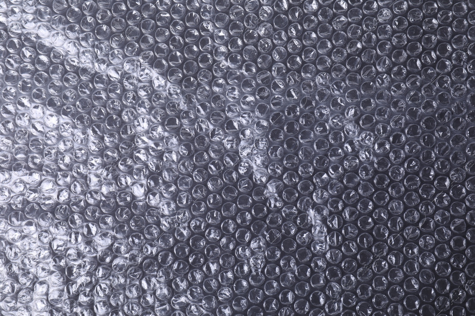 Photo of Transparent bubble wrap on black background, top view