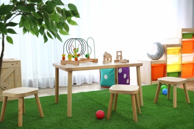 Stylish playroom interior with toys and modern wooden furniture