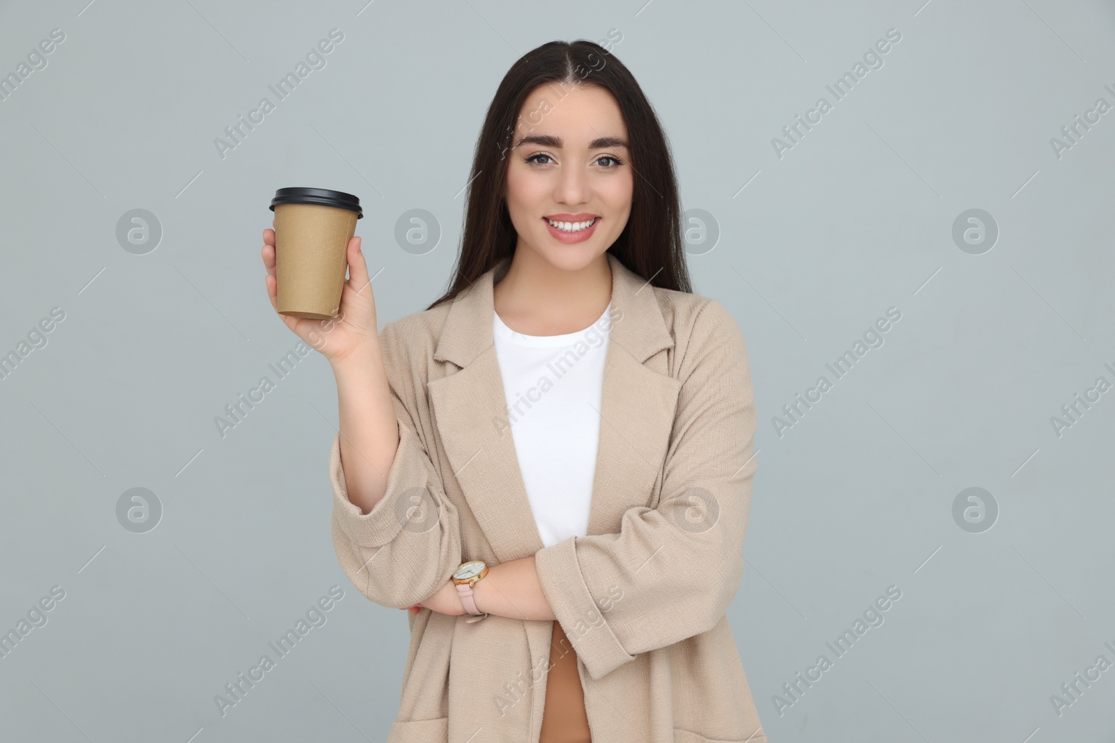 Photo of Young female intern with cup of drink on grey background