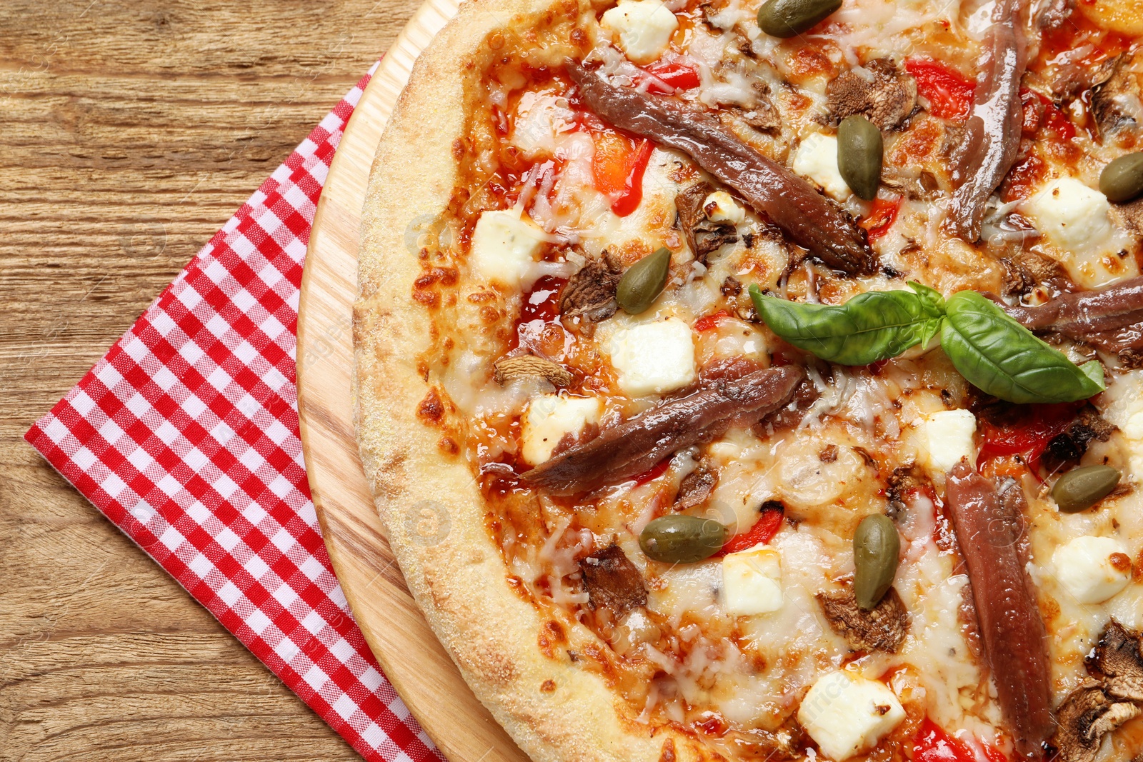 Photo of Tasty pizza with anchovies, basil and olives on wooden table, top view