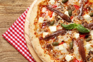 Photo of Tasty pizza with anchovies, basil and olives on wooden table, top view