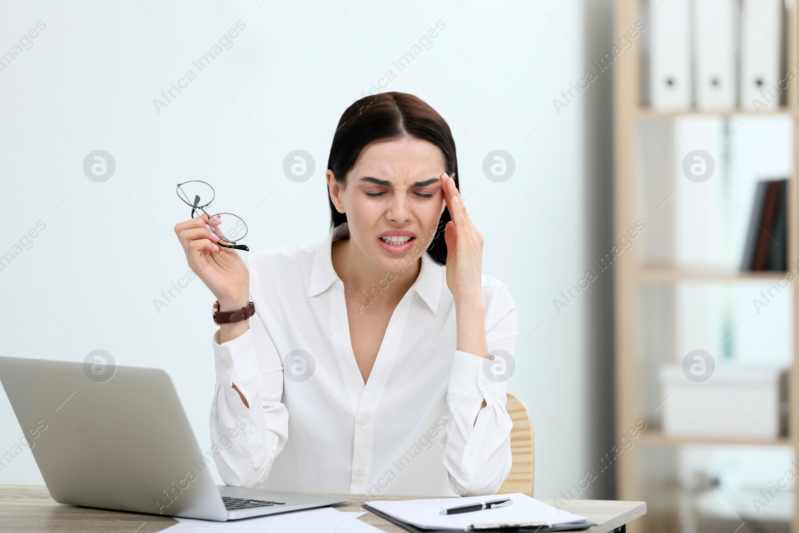 Photo of Woman suffering from migraine at workplace in office