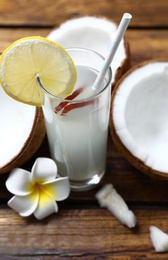 Photo of Composition with glass of coconut water and lemon on wooden table, closeup