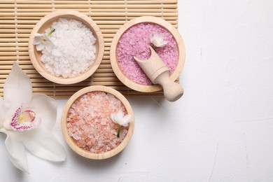 Photo of Different types of sea salt and flowers on light table, flat lay. Spa products