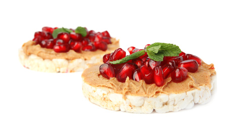 Puffed rice cakes with peanut butter, pomegranate seeds and mint isolated on white