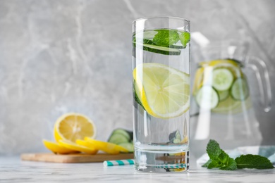 Photo of Refreshing water with cucumber, lemon and mint on white marble table. Space for text